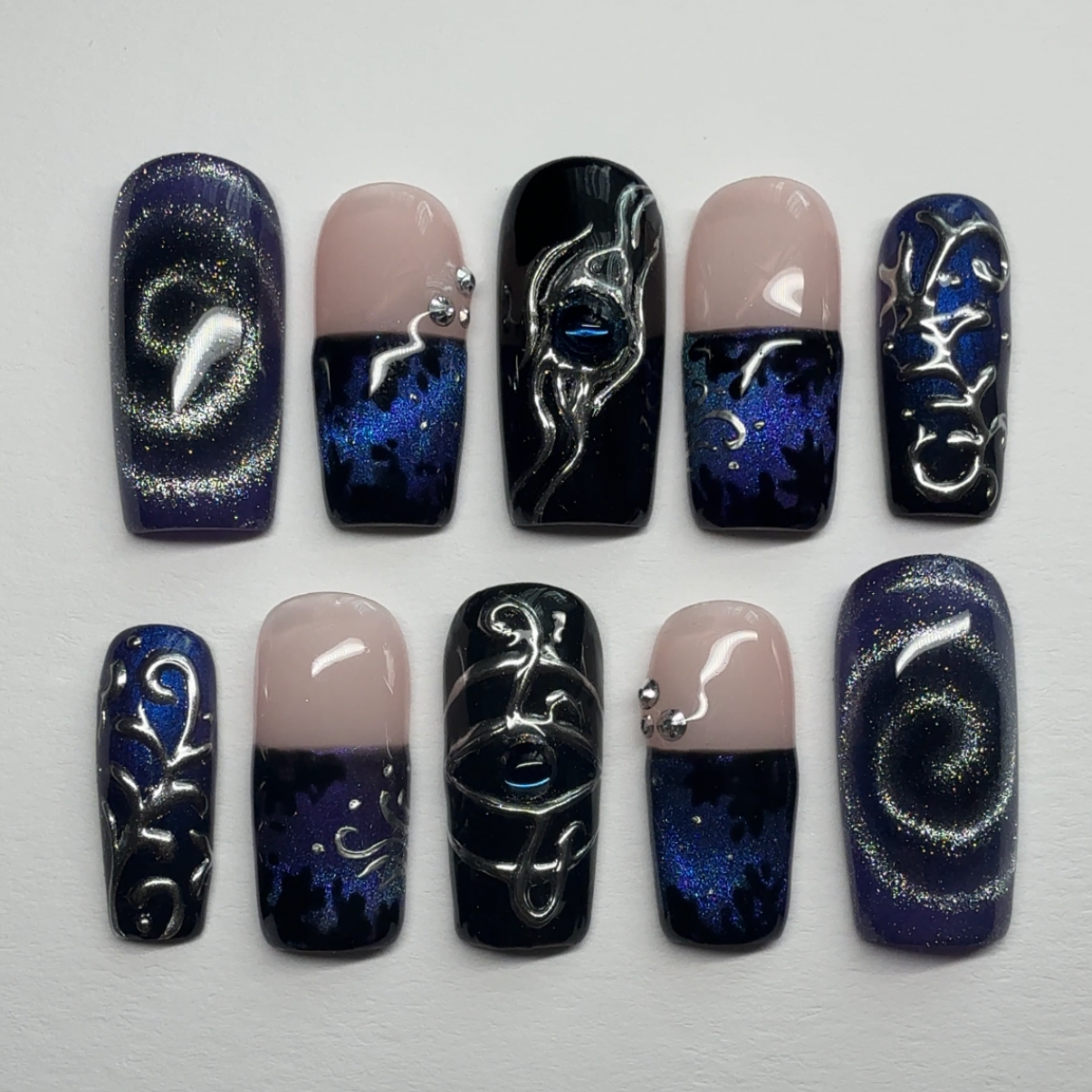 Nail art with black, blue, and beige designs on a white background